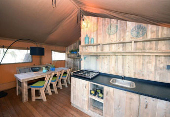Interior de una tienda de glamping con cocina y comedor de madera en Camping Arena Stoja, Croacia.
