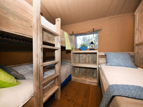 Interior de un dormitorio con literas y una cama individual en una tienda safari en Camping Arena Stoja, Croacia.