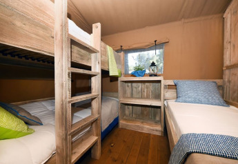Interior of a bedroom with bunk beds and a single bed in a safari tent at Camping Arena Stoja, Croatia.