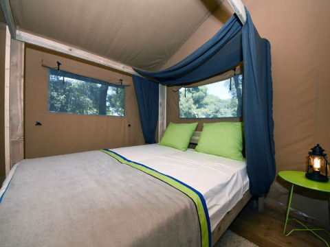 Inde i et safari telt med dobbeltseng og grønne puder på Camping Arena Stoja, Kroatien, til glamping.