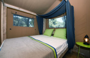 Inde i et safari telt med dobbeltseng og grønne puder på Camping Arena Stoja, Kroatien, til glamping.