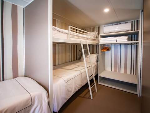 Camera compatta moderna con letto a castello e singolo presso Camping Villa al Camping Arena Stoja, Croazia.