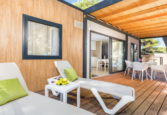 Terrazza esterna del Camping Villa Sea View con lettini, tavolo, sedie e vista panoramica sulla natura.