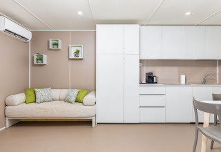 Moderne campinglodge met sofa, keuken en minimalistisch interieur bij Camping Arena Stoja, Kroatië.