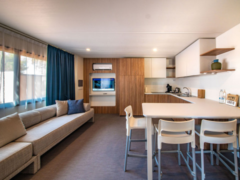 Soggiorno e cucina moderni nella Deluxe Camping Villa al Camping Arena Stoja, Croazia, con divano e tavolo da pranzo.