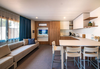 Sala y cocina modernas en la Deluxe Camping Villa de Camping Arena Stoja, Croacia, con sofá y mesa comedor.