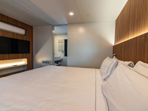Schlafzimmer der Deluxe Camping Villa im Camping Arena Stoja, Kroatien mit Doppelbett und modernem Design.