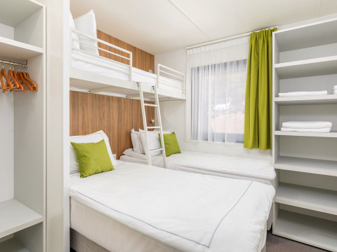 Modernes Schlafzimmer mit Etagenbett, zwei Einzelbetten und grünen Akzenten in der Deluxe Camping Villa.