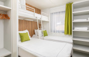 Modern bedroom with bunk bed, two single beds, and green accents in the Deluxe Camping Villa, Croatia.
