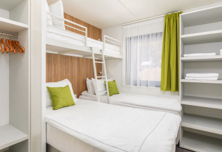 Modernes Schlafzimmer mit Etagenbett, zwei Einzelbetten und grünen Akzenten in der Deluxe Camping Villa.