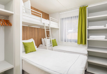 Camera moderna con letto a castello, due letti singoli e dettagli verdi nella Deluxe Camping Villa, Croazia.