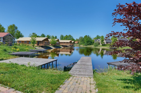 Vakantiepark Eigen Wijze in Flevoland met houten steiger, water, glampingtenten en groene natuur.