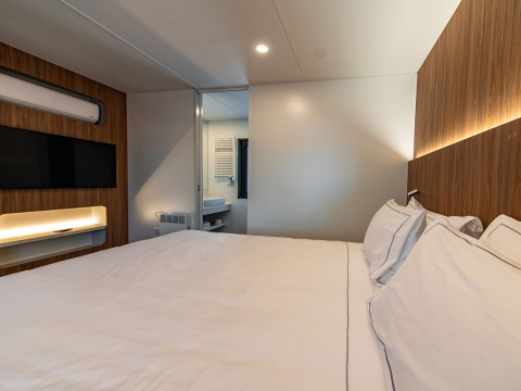 Moderne slaapkamer in Deluxe Camping Villa Sea View bij Camping Arena Stoja, Kroatië, met houtafwerking.