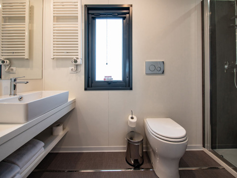 Salle de bain moderne avec fenêtre, lavabo, WC et douche à la Deluxe Camping Villa Sea View en Croatie.