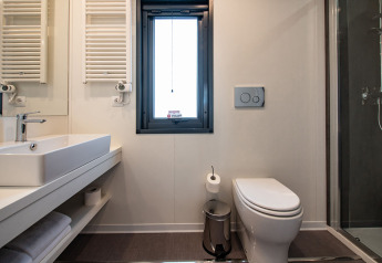 Salle de bain moderne avec fenêtre, lavabo, WC et douche à la Deluxe Camping Villa Sea View en Croatie.