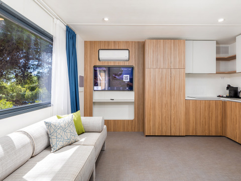 Soggiorno moderno nella Deluxe Camping Villa First Row al Camping Arena Stoja, Croazia, con divano e cucina.
