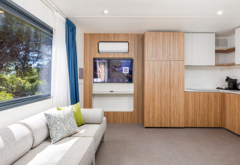Modernes Wohnzimmer in der Deluxe Camping Villa First Row im Camping Arena Stoja, Kroatien, mit Sofa und Küche.