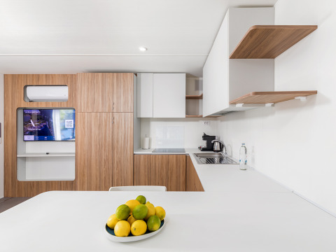 Moderne keuken met houten kasten, witte werkbladen en fruitschaal in Deluxe Camping Villa First Row, Kroatië.