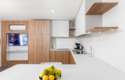 Modern kitchen with wood cabinets, white countertops, and fruit bowl in Deluxe Camping Villa First Row, Croatia.