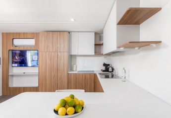Modern kitchen with wood cabinets, white countertops, and fruit bowl in Deluxe Camping Villa First Row, Croatia.