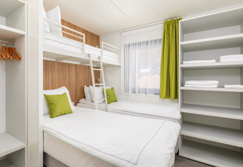 Moderne campingvilla med køjeseng, enkeltsenge, grønt gardin og åbne hylder i Camping Arena Stoja, Kroatien.
