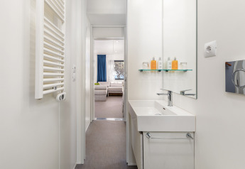 Baño moderno con lavabo blanco, espejo y área de descanso en Deluxe Camping Villa First Row, Arena Stoja, Croacia.