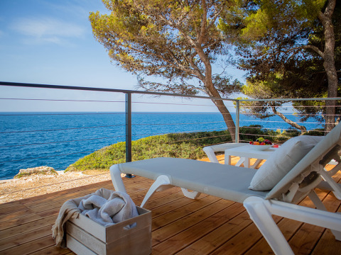 Villa deluxe con lettini e vista mare presso Camping Arena Stoja in Croazia, circondata da pini.