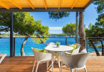 Wooden terrace with table and chairs, sea view, pine trees at Camping Villa First Row, Arena Stoja, Croatia.