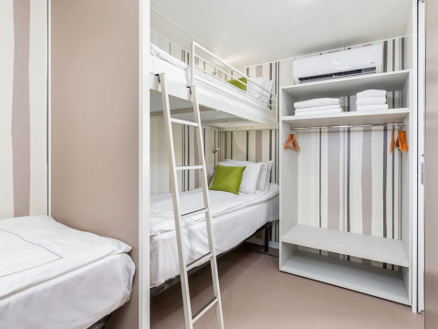 Chalet moderno al Camping Arena Stoja in Croazia con letti a castello, armadio aperto e biancheria fresca.