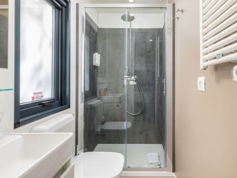 Modernes Badezimmer mit Glasdusche, weißer Toilette und Fenster in einem Chalet auf Camping Arena Stoja, Kroatien.