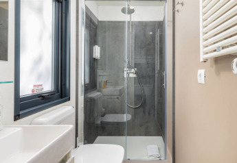 Modern bathroom with glass shower, white toilet, and window in a chalet at Camping Arena Stoja, Croatia.