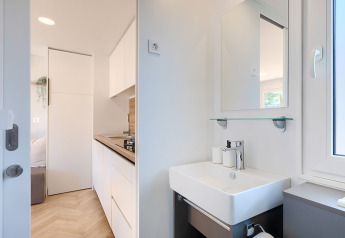 Interni di una lodge moderna con piccolo lavabo, specchio e cucina adiacente dal design minimalista.