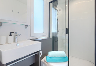 Modern lodge bathroom featuring a shower, sink, toilet, and neatly folded towels, clean and bright.
