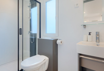 Bagno moderno e luminoso in un lodge, dotato di doccia, wc, lavandino e specchio con arredo minimalista.