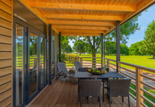 Covered wooden terrace of Park Riviera Adria Blue Seaside at Camping Park Umag, Croatia, overlooking green lawn.