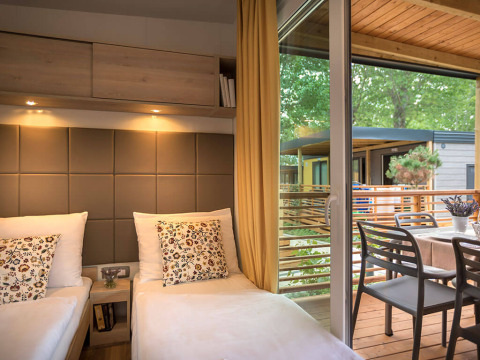 Interior view of Lopar Garden Home lodge with two beds and terrace access at Valamar Camping San Marino, Croatia.
