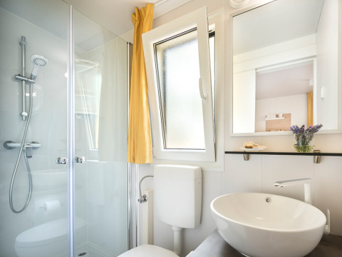 Bright, modern bathroom with shower, sink, open window and mirror at Lopar Garden Home in Croatia.