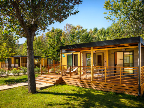 Lopar Garden Home lodge featuring a wooden deck and lush greenery, set in a tranquil and sunny garden environment.