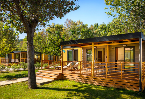 Lopar Garden Home lodge featuring a wooden deck and lush greenery, set in a tranquil and sunny garden environment.