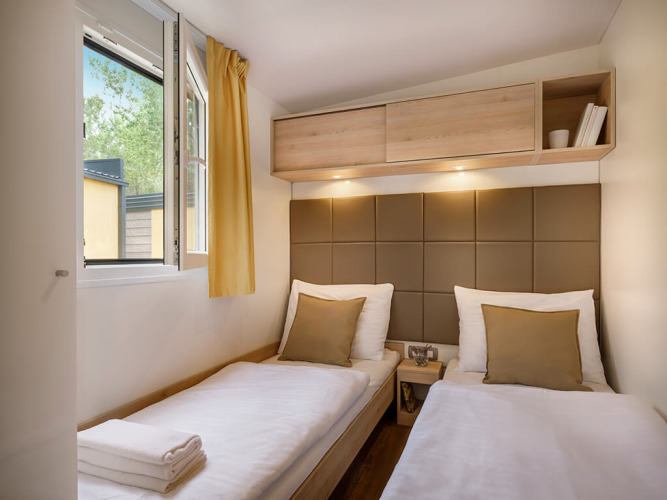 Chambre à deux lits modernes avec fenêtre ouverte et décoration soignée à Vela Bay Home, Valamar Camping Baška, Croatie.