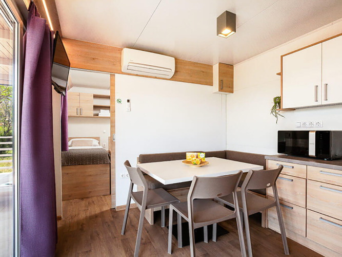 Interior of a Sunny Beach Home lodge at Valamar Camping Baška, Croatia, with dining table and kitchenette.