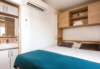 Dormitorio moderno en Sunny Beach Home de Valamar Camping Baška, Croacia, con cama doble y muebles de almacenaje.