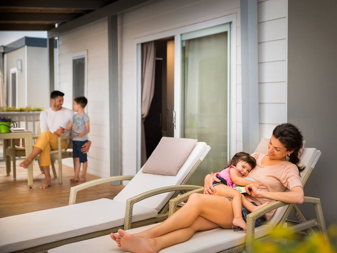 Famiglia che si rilassa fuori da un alloggio al Krk Home di Valamar Camping Krk in Croazia, atmosfera serena.