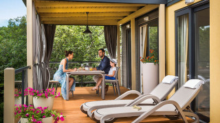Famiglia fa colazione sulla terrazza di Bella Vista Home lodge circondata da piante e fiori colorati.