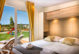 Slaapkamer in Bella Vista Home op Valamar Camping Krk, Kroatië, met terras en uitzicht op speeltuin.