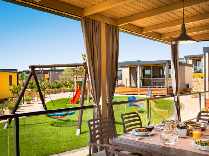 Uitzicht vanaf het overdekte terras bij Bella Vista Home in Valamar Camping Krk, met speeltuin en lodges.