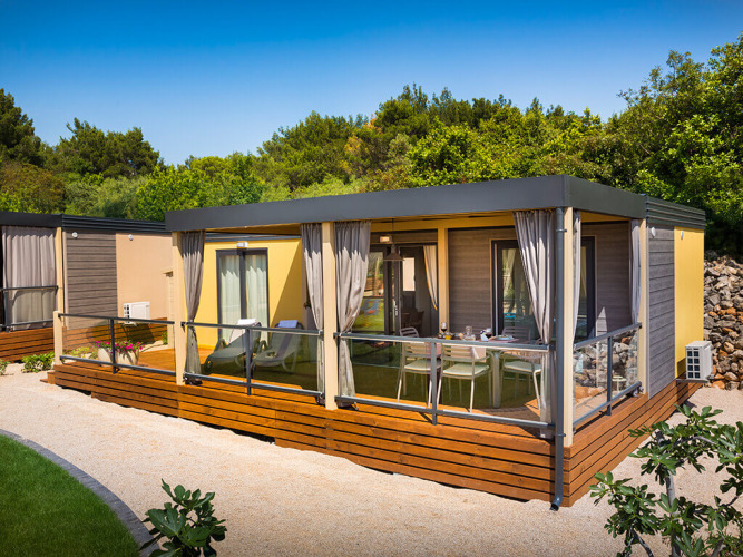 Udendørs billede af Bella Vista Home lodge med terrasse på Valamar Camping Krk i Kroatien, omgivet af træer.