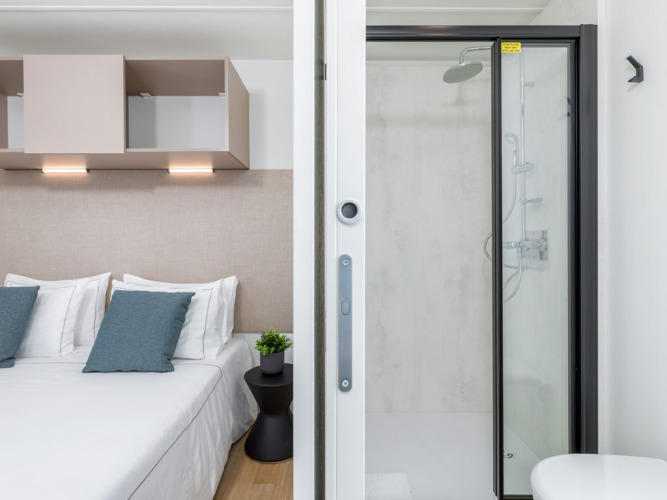 Modernes Camping Home bei Camping Arena Stupice in Kroatien mit Schlafzimmer, Doppelbett und Dusche.