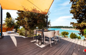 Deck with dining table under shade sail overlooking the sea at Family Holiday Home Pool, Camping Porton Nature Hideouts.