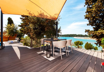 Terraza con mesa para comer bajo toldo, vista al mar en Family Holiday Home Pool, Camping Porton Nature Hideouts, Croacia.